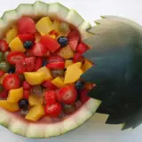 Deliciosa macedonia de frutas servida en una sandía tallada, con fresas, melocotón, uvas y arándanos.