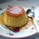 Delicioso flan de huevo casero con caramelo líquido, servido en un plato con dibujos infantiles.
