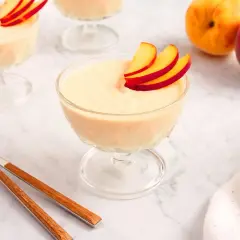 Delicioso mousse de melocotón en copas de cristal, decorado con finas láminas de melocotón.