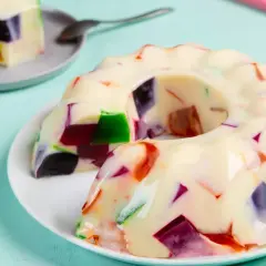 Gelatina con leche condensada, con trozos de colores vibrantes incrustados, como un mosaico dulce.