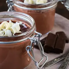 Deliciosa panna cotta de chocolate en frascos, decorada con rizos de chocolate blanco. Dos porciones listas para disfrutar.