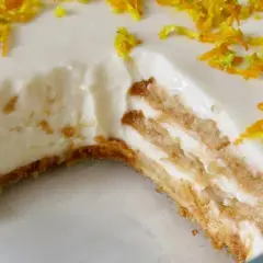 Tarta de limón sin horno, con capas de galleta y crema, decorada con ralladura de limón y naranja.