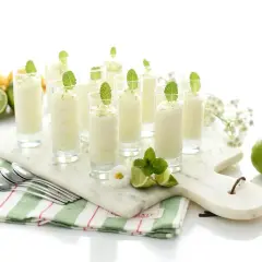 Delicioso mousse de limón en vasitos, decorado con menta y ralladura de limón. Frescura y sabor en cada bocado.