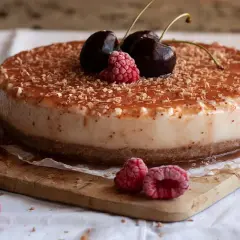Tarta de queso con leche condensada, cubierta de mermelada y virutas de chocolate, decorada con cerezas y frambuesas.