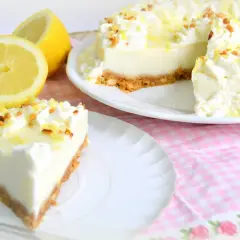 Deliciosa tarta de limón con cuajada y leche condensada, decorada con nata y ralladura de limón.