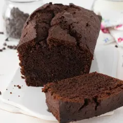 Un delicioso plum cake de chocolate, con una rebanada separada y chispas de chocolate esparcidas.