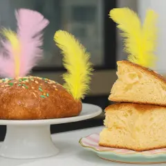 Pan dulce decorado con plumas de colores y chispas, ideal para una receta mona de pascua.