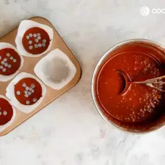 Molde con magdalenas de chocolate listas para hornear y un bol con masa de chocolate y cucharón.