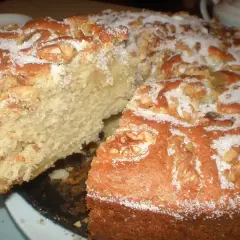 Un delicioso bizcocho de manzana y nueces, espolvoreado con azúcar, con una rebanada retirada.