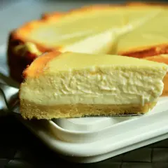 Una rebanada cremosa de tarta de queso Philadelphia, con su base dorada y relleno suave, lista para ser disfrutada.