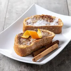 Dos deliciosas torrijas, con azúcar y canela, decoradas con piel de naranja y varas de canela. El mejor pan para torrijas, esponjoso y dorado.