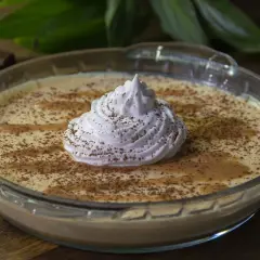 Delicioso mousse de dulce de leche en un bol de vidrio, coronado con crema batida y espolvoreado con cacao.