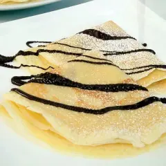 Deliciosos crepes doblados, espolvoreados con azúcar glas y cubiertos con un glaseado de chocolate. Una receta crepes perfecta para cualquier ocasión.