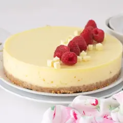 Deliciosa tarta de chocolate blanco adornada con frambuesas frescas y trocitos de chocolate.