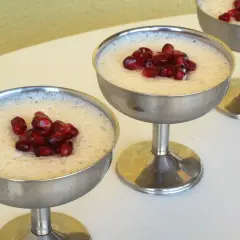 Delicioso mousse de leche condensada Thermomix, coronado con granada, servido en copas metálicas.