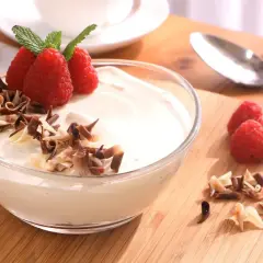 Delicioso mousse de chocolate blanco adornado con frambuesas frescas y virutas de chocolate.