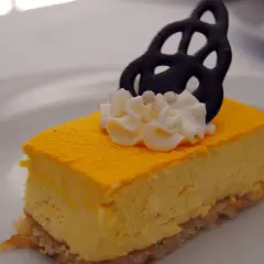 Deliciosa tarta de mango con crema batida y un adorno negro.