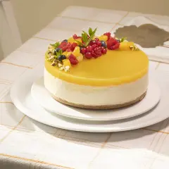 Deliciosa tarta de mango y queso, cubierta con gelatina amarilla y decorada con frutos rojos y pistachos.