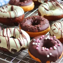 Deliciosos donuts al horno cubiertos de chocolate, glaseado blanco y chispas de colores.