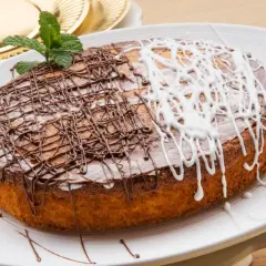 Tarta de zanahoria y coco, decorada con glaseado de chocolate y blanco, y una ramita de menta.