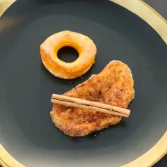 Rosquillas de Alcalá y torrija con canela, servidas en plato negro con borde dorado.