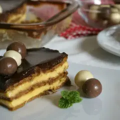 Tarta de la abuela con flanín, capas de galleta y crema, cubierta de chocolate y decorada con bombones. ¡Un postre casero irresistible!