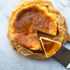 Tarta de queso congelada, dorada y cremosa, con una porción servida en una espátula.