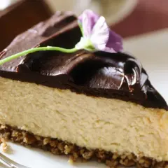 Deliciosa tarta de queso y chocolate, con una capa cremosa y cobertura brillante, decorada con una flor.