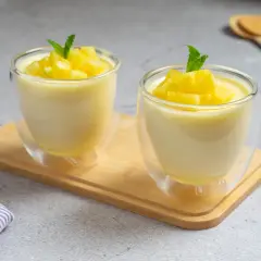 Dos copas de cristal con un delicioso mousse de piña, decoradas con trocitos de piña y menta.