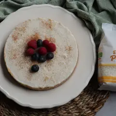 Deliciosa tarta de arroz, cubierta con canela y decorada con frambuesas y arándanos. A su lado, un paquete de arroz SOS Especial Postres.