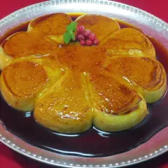 Delicioso flan de arroz con leche con caramelo dorado, decorado con bayas rojas y menta.