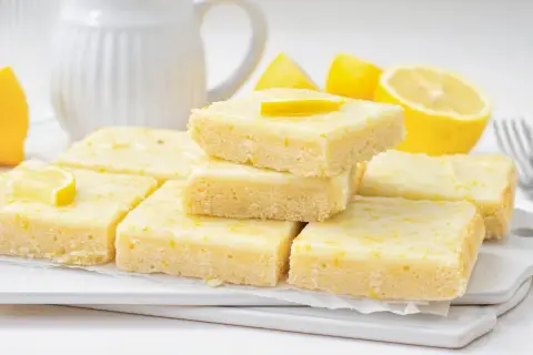 Deliciosos brownie de limón, con una capa superior glaseada y ralladura de limón.