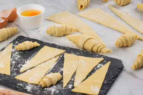 Ingredientes para la receta de cruasanes: masa enrollada, huevos batidos y cáscaras de huevo.