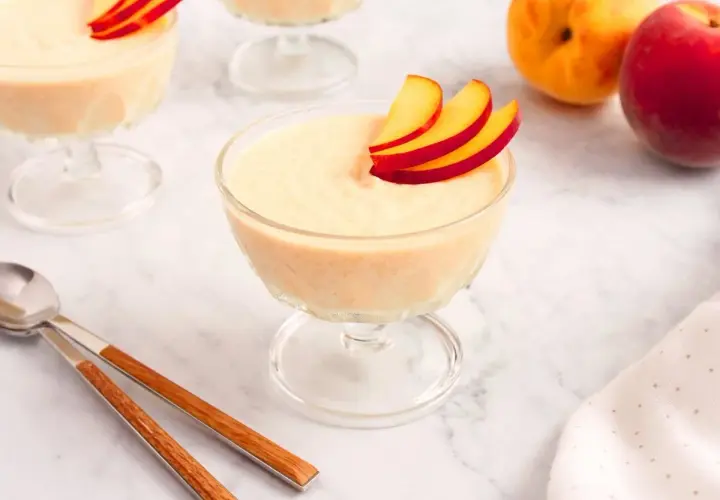 Delicioso mousse de melocotón en copas de cristal, decorado con finas láminas de melocotón.