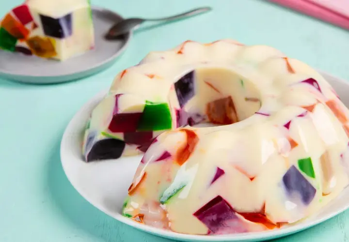 Gelatina con leche condensada, con trozos de colores vibrantes incrustados, como un mosaico dulce.