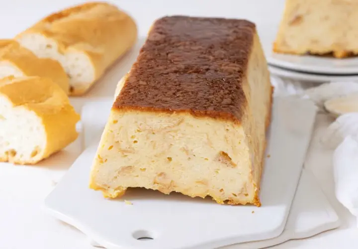 Un delicioso pudin de pan duro, con trozos de pan crujiente y una cobertura dorada.
