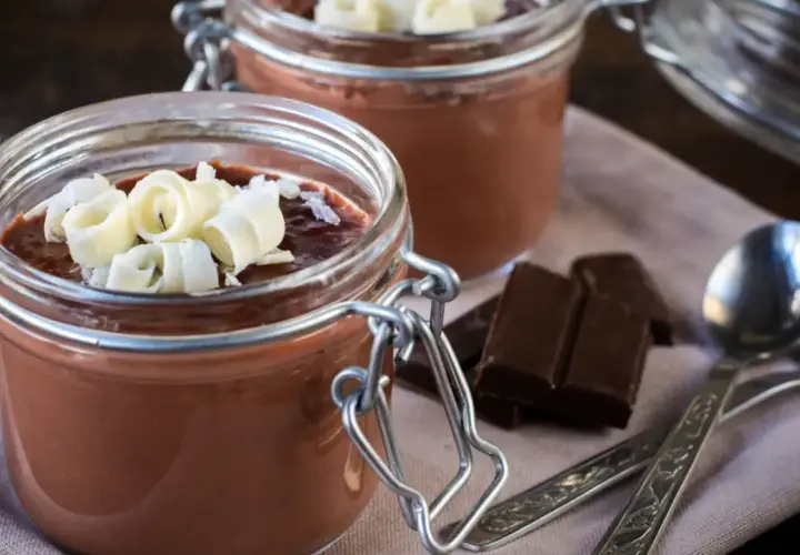 Deliciosa panna cotta de chocolate en frascos, decorada con rizos de chocolate blanco. Dos porciones listas para disfrutar.
