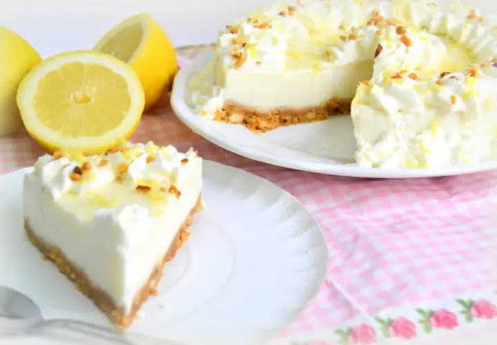 Deliciosa tarta de limón con cuajada y leche condensada, decorada con nata y ralladura de limón.