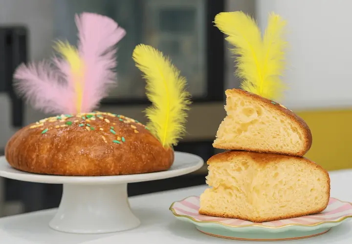 Pan dulce decorado con plumas de colores y chispas, ideal para una receta mona de pascua.