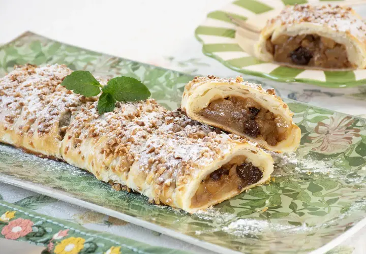 Deliciosa trenza de hojaldre rellena de manzana y pasas, espolvoreada con azúcar glas y nueces picadas.