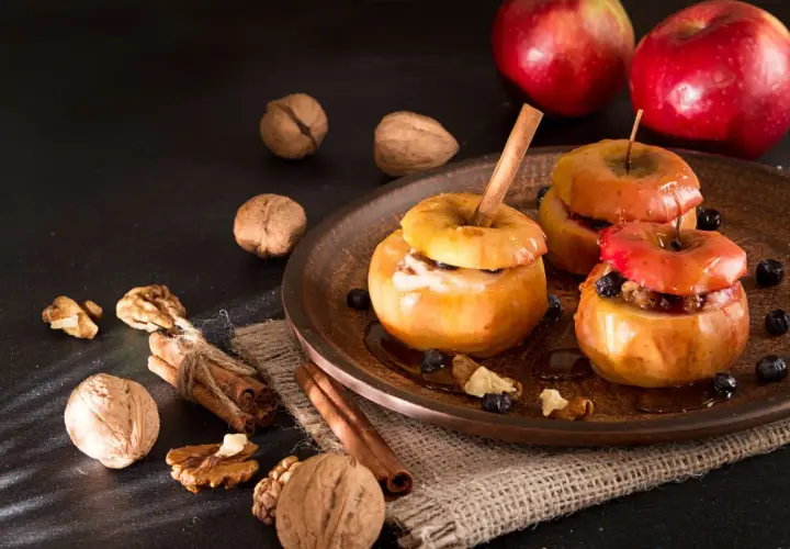 Deliciosas manzanas al horno con canela, nueces y arándanos, un postre casero perfecto para el otoño.