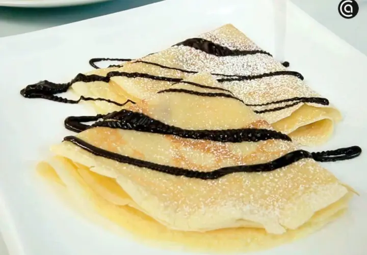 Deliciosos crepes doblados, espolvoreados con azúcar glas y cubiertos con un glaseado de chocolate. Una receta crepes perfecta para cualquier ocasión.