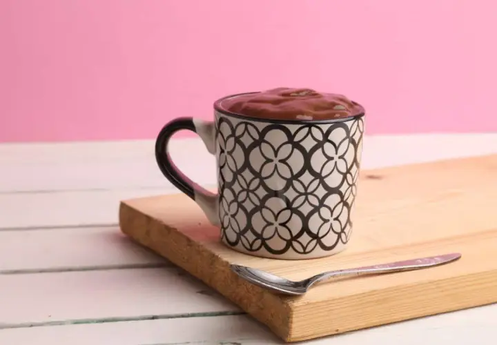 Taza con un delicioso oreo mug cake, lista para disfrutar con una cuchara.