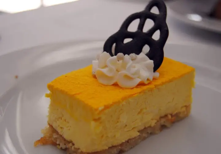 Deliciosa tarta de mango con crema batida y un adorno negro.