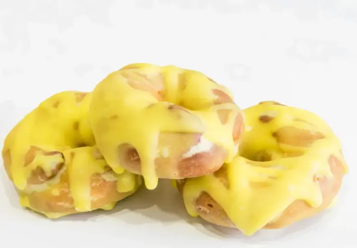 Tres rosquillas de San Isidro cubiertas con un glaseado amarillo brillante, listas para disfrutar.