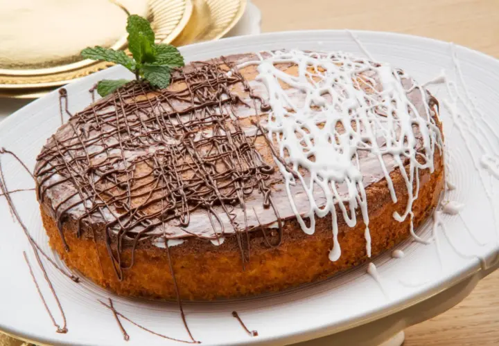 Tarta de zanahoria y coco, decorada con glaseado de chocolate y blanco, y una ramita de menta.