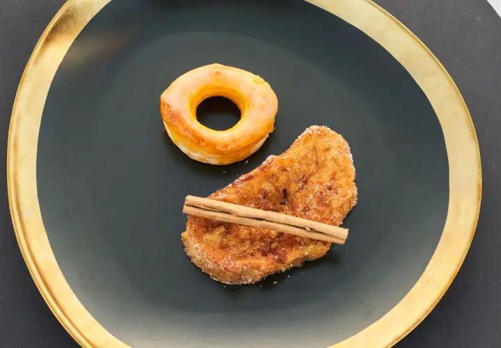 Rosquillas de Alcalá y torrija con canela, servidas en plato negro con borde dorado.