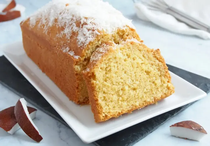 Bizcocho de coco esponjoso, cubierto con coco rallado y acompañado de trozos de coco fresco. ¡Un postre tropical delicioso!
