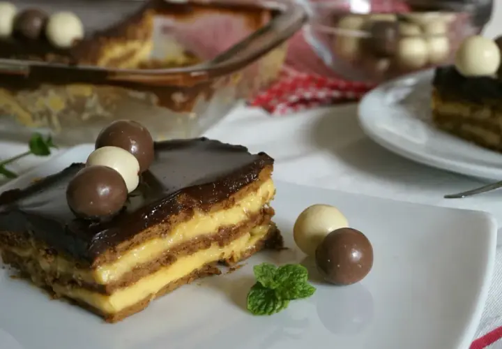 Tarta de la abuela con flanín, capas de galleta y crema, cubierta de chocolate y decorada con bombones. ¡Un postre casero irresistible!
