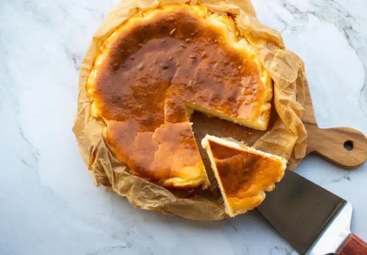 Tarta de queso congelada, dorada y cremosa, con una porción servida en una espátula.